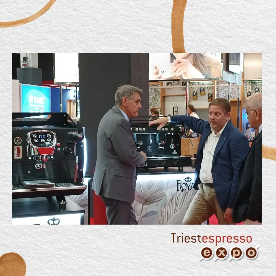 Two people talking next to an espresso machine